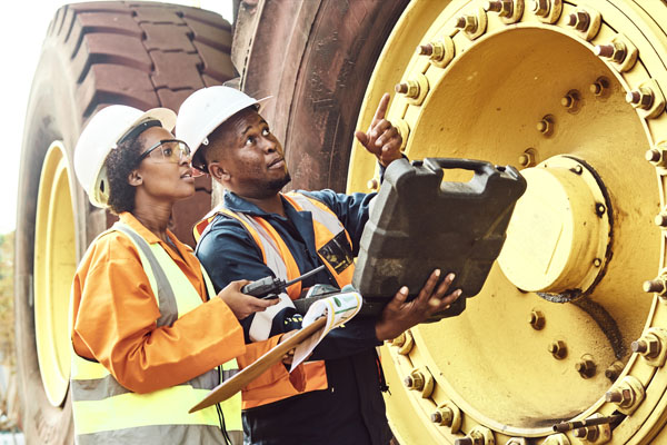 a man and a woman in hard hats looking at heavy machinery