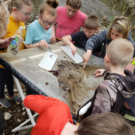 4H children looking through debris on a scrim table