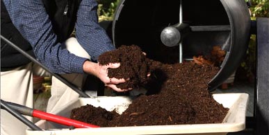 compost tumbler being emptied into a wheel barrow