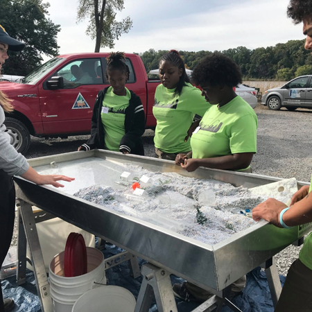 young women sifting through stream contents at a table